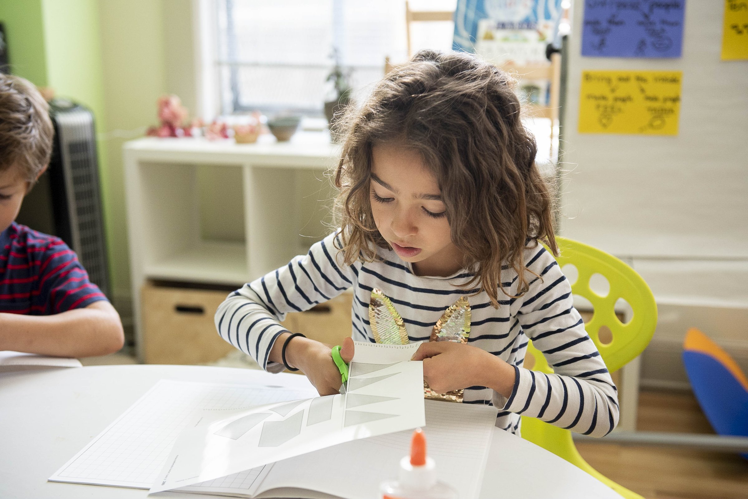 A young student concentrating on a worksheet at a classroom table