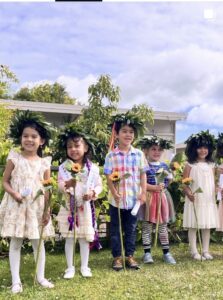 Children in leafy crowns holding sunflowers on the lawn