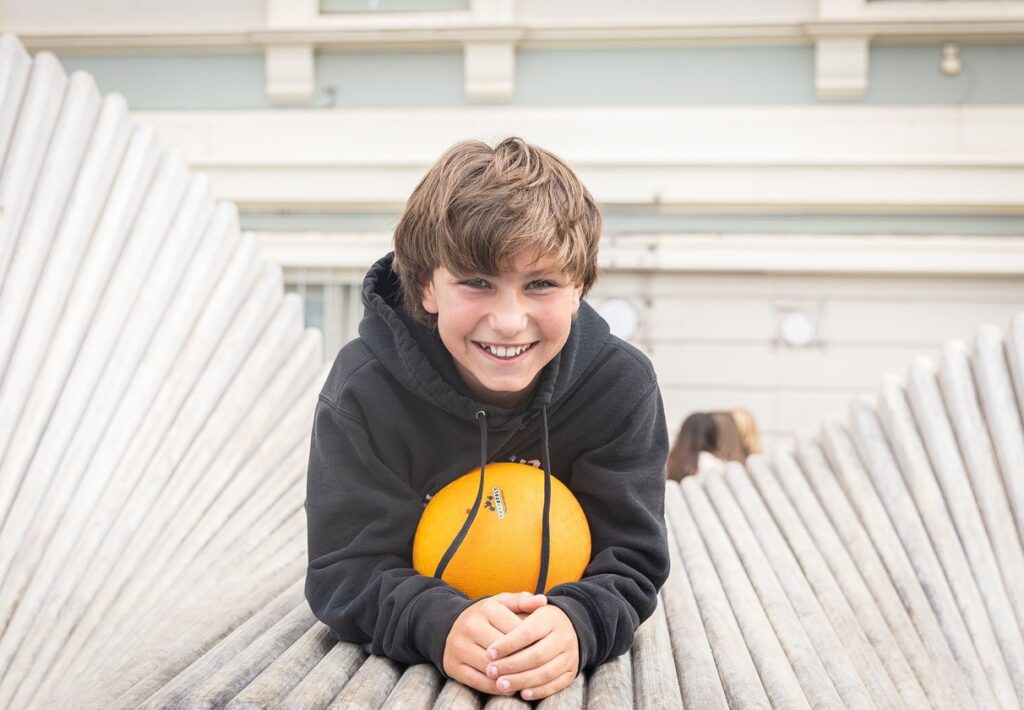 Smiling middle school student holding a ball on the playground