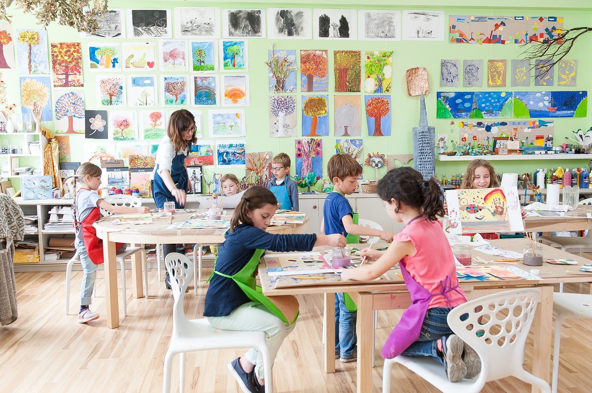 Children working at tables in a classroom lined with student artwork