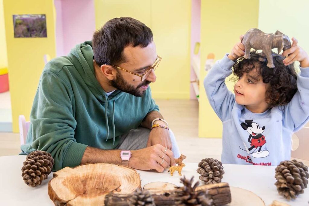 A teacher and a preschooler exploring pine cones and a wooden slice